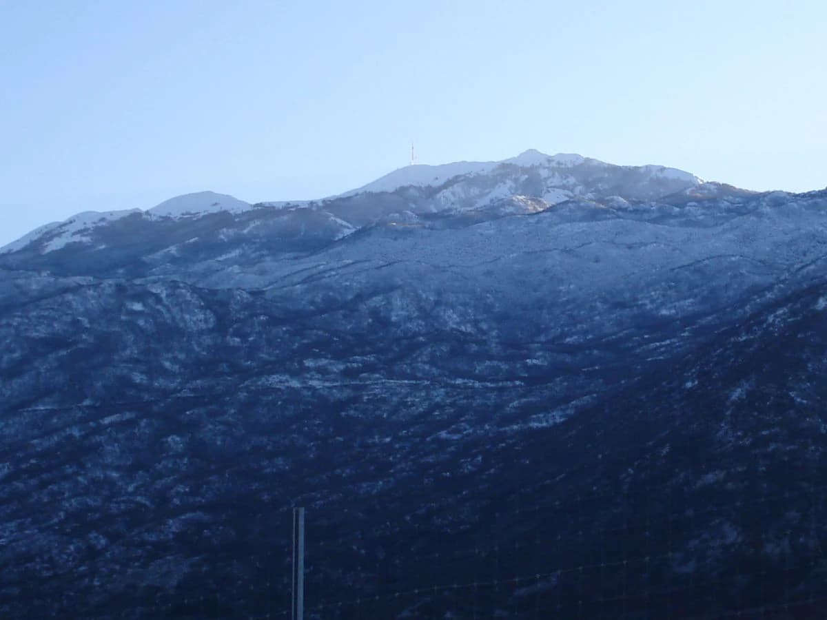 Wide view of snow-covered mountain range with TV transmitter tower visible on the left side