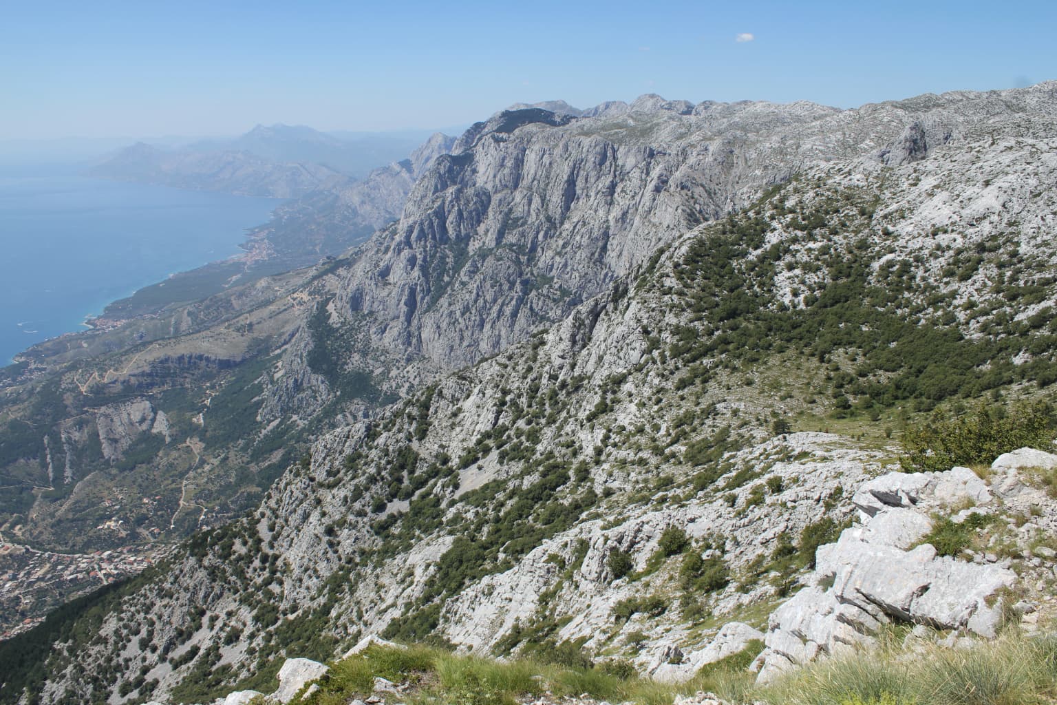 Rocky mountain slopes descending toward the sea with coastal areas visible in the distance