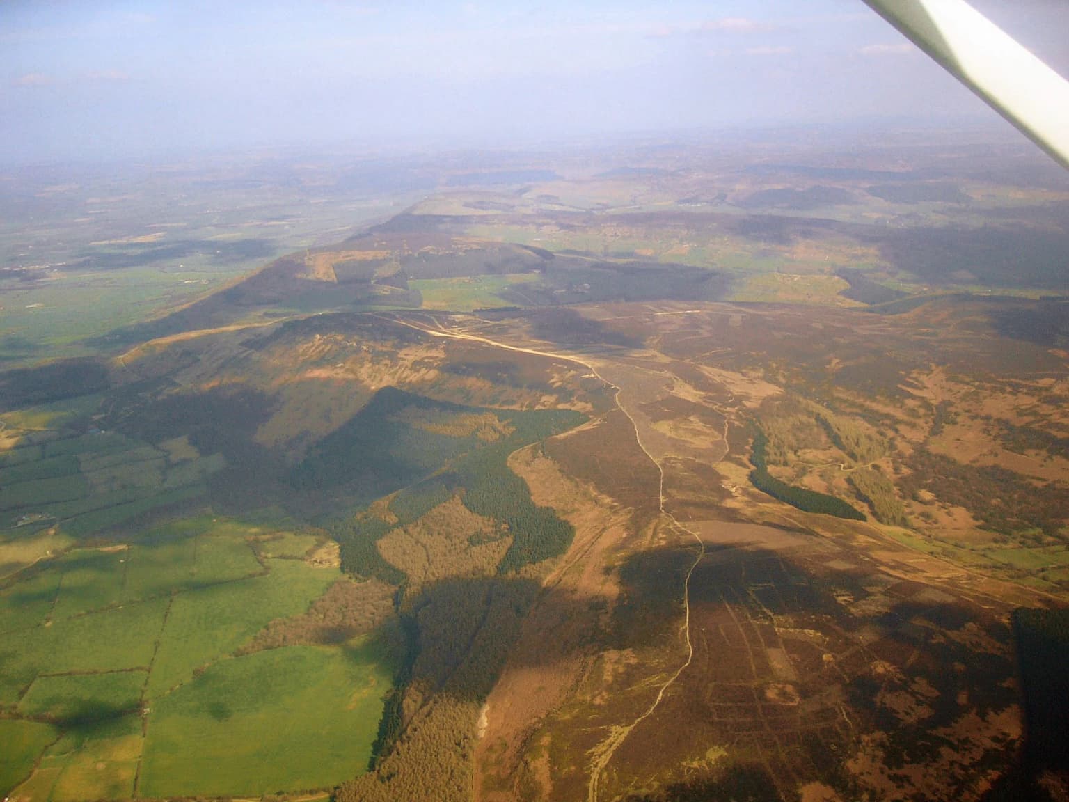 Aerial photograph of the North York Moors national park with open fields, moorland, and distant hills under a partly cloudy sky