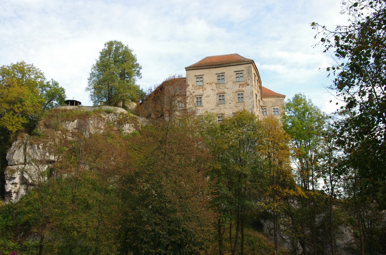 Pieskowa Skała Castle on a rocky cliff surrounded by forest with autumn-colored trees
