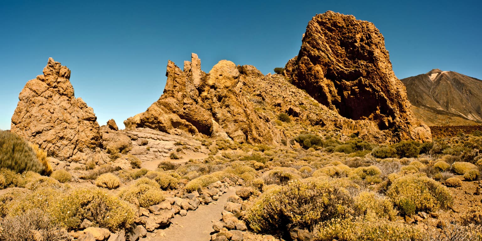 Rock formations with sparse vegetation under clear blue sky in Teide National Park