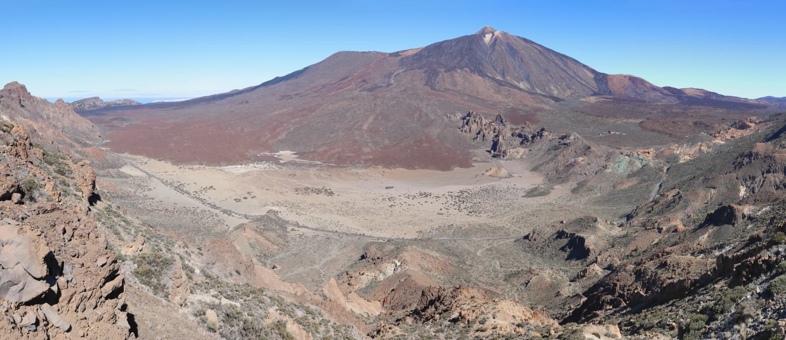 Wide landscape view of Mount Teide volcano and Cañadas del Teide caldera with rocky terrain under clear blue sky