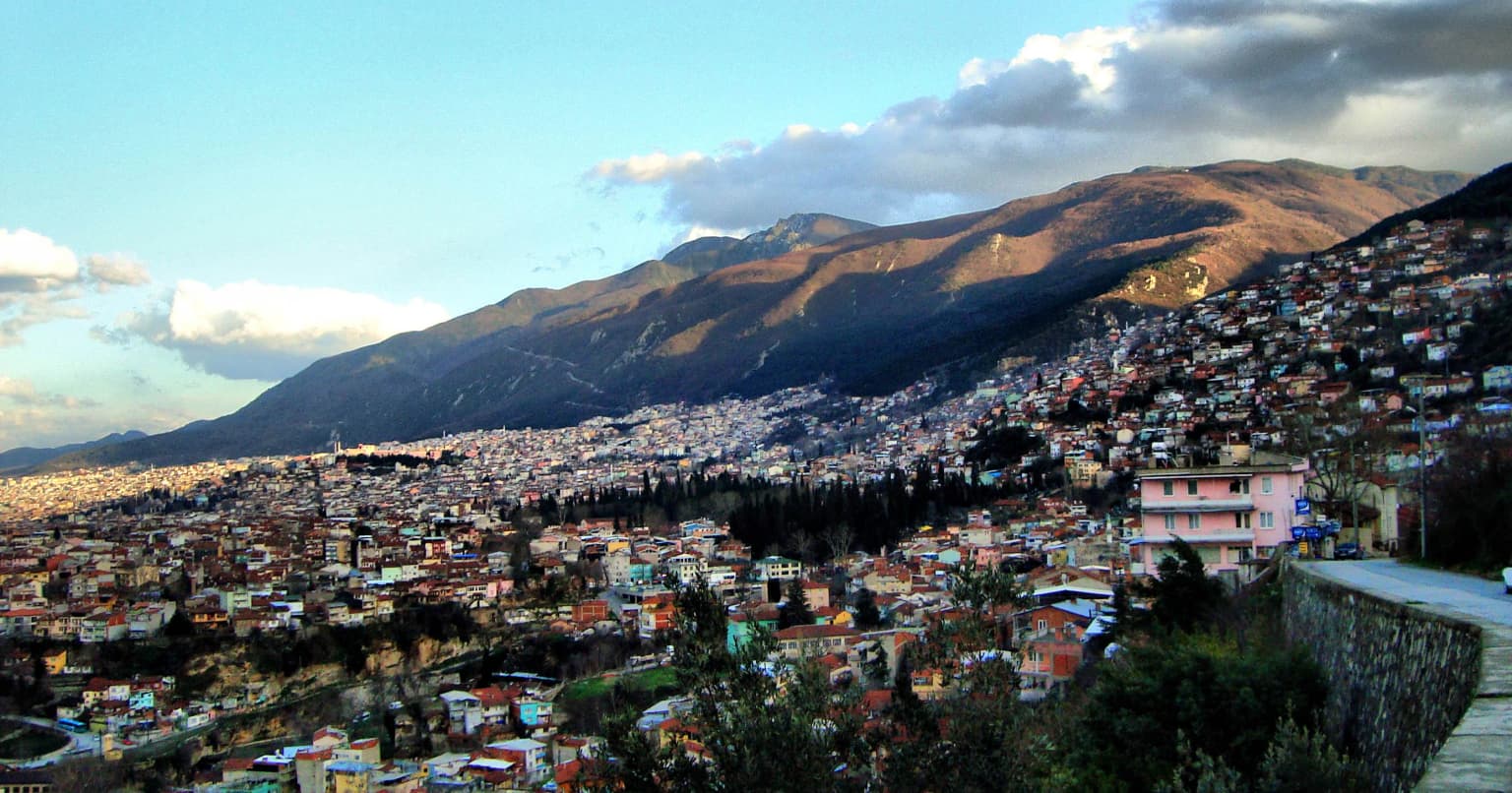 Panoramic view of Bursa city with mountains in the background under a partly cloudy sky