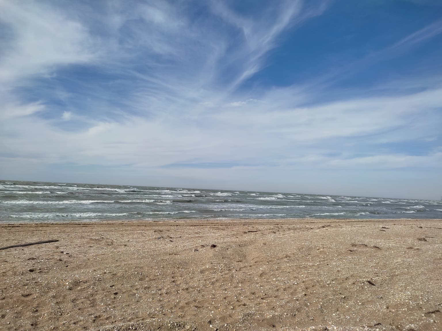 Sandy beach with gentle ocean waves and scattered clouds in the sky