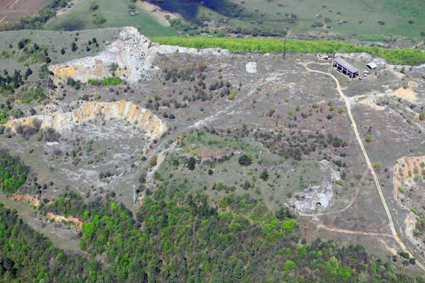 Aerial view of Esztramos Hill showing rocky terrain, sparse vegetation, a small building, and a dirt road.