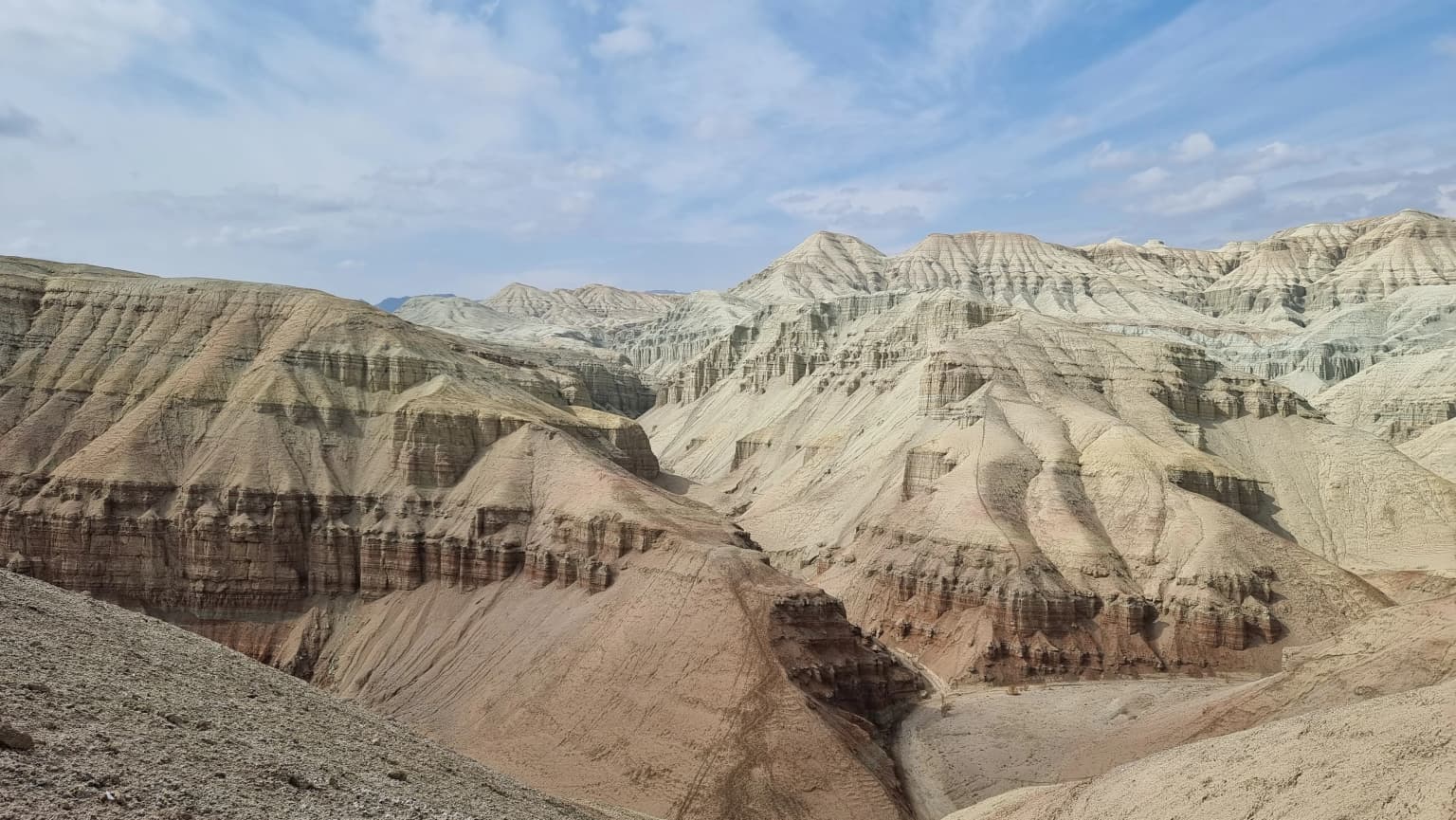 A wide view of layered desert mountains with rocky terrain under a partly cloudy sky