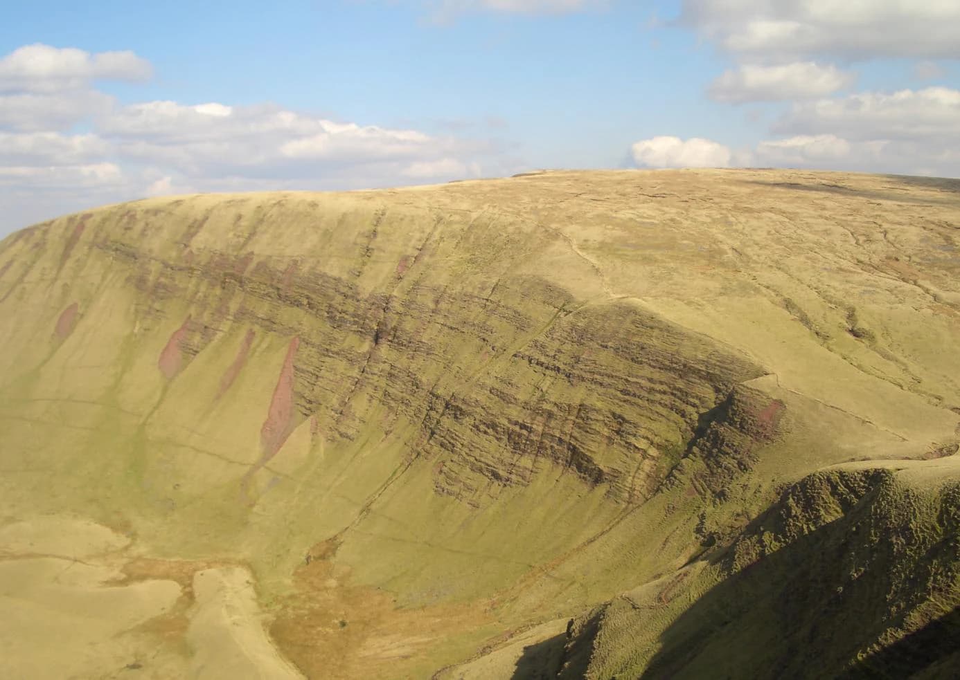 Large mountain with layered rock formations under a partly cloudy sky