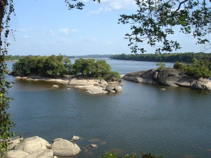 Río que fluye a través del Parque Nacional Caura con islas rocosas, orilla boscosa y cielo azul claro