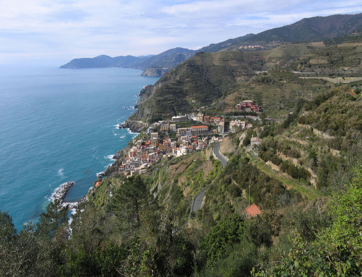 Coastal village with terraced hillsides and blue sea visible from elevated viewpoint