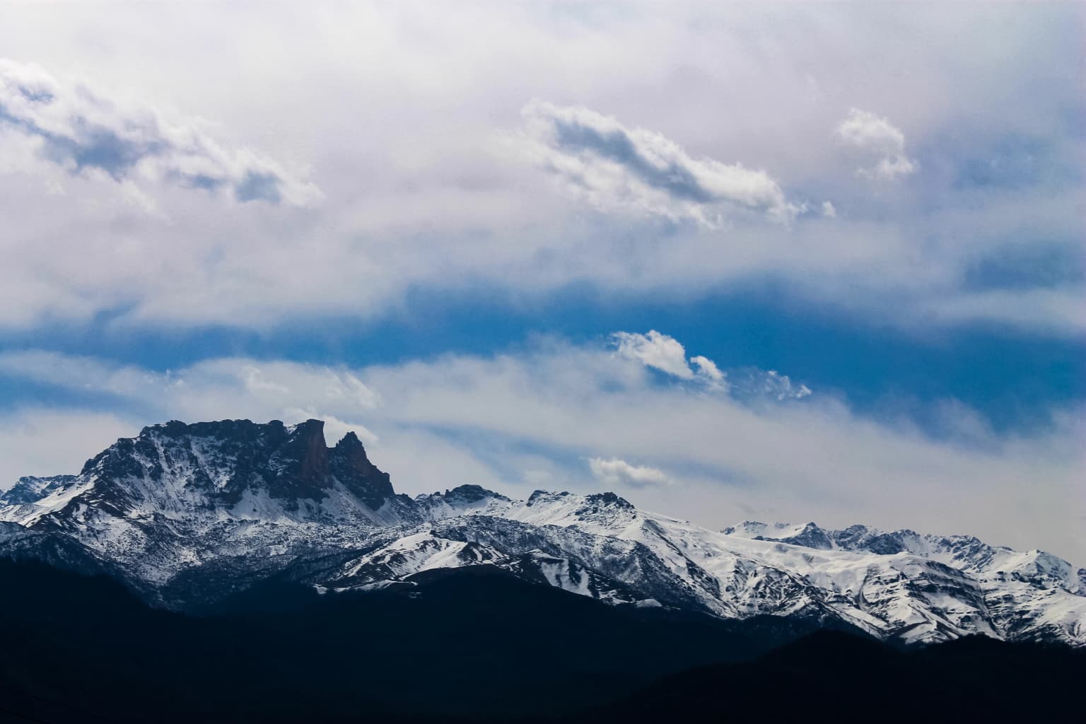 Snow-covered mountain peaks with clouds in the sky