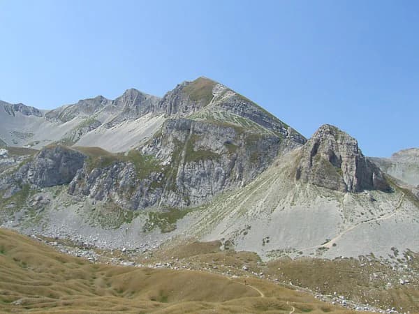 Rocky mountain peaks with grassy slopes and a clear blue sky in Gran Sasso and Monti della Laga National Park.