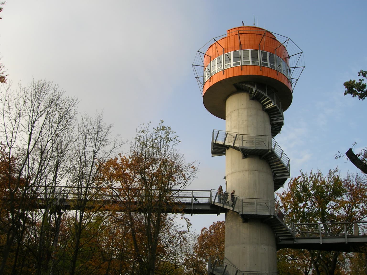 Observation tower with spiral staircase and connecting walkway surrounded by trees with autumn foliage