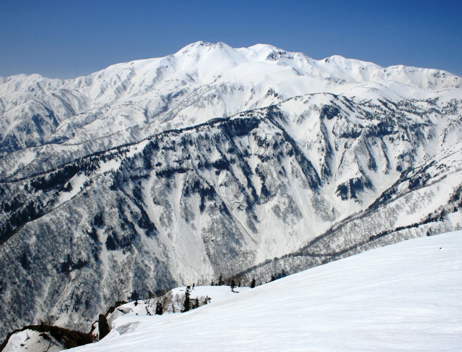 Cordillera montañosa cubierta de nieve con el monte Haku como pico central bajo un cielo azul despejado