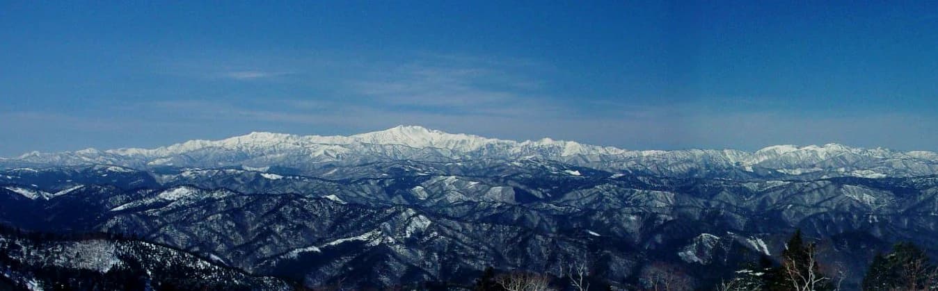 Vista panorámica de picos y crestas montañosas cubiertas de nieve bajo un cielo azul despejado