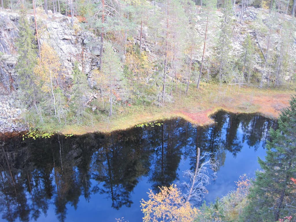 Calm lake reflecting rocky cliffs and forested shoreline with autumn foliage