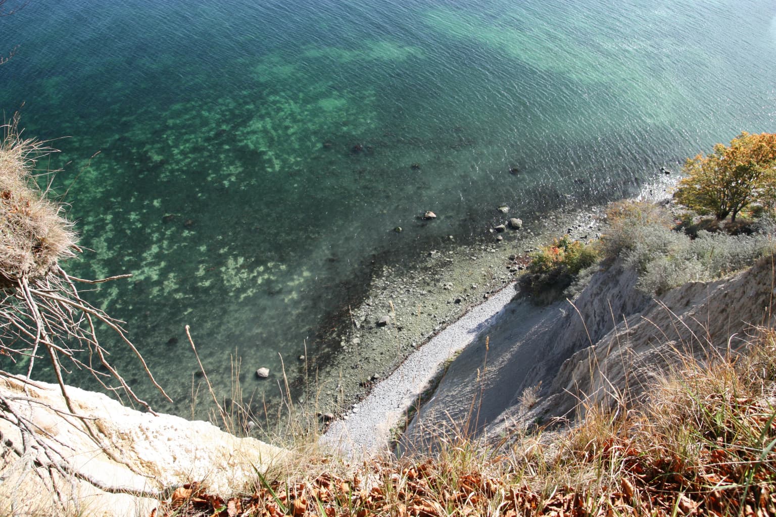 White chalk cliffs with turquoise water and rocky shoreline