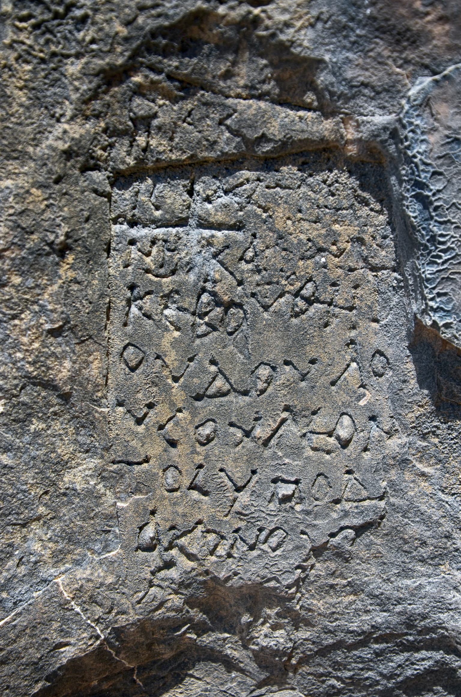 Close-up of ancient carved inscriptions on a weathered rock face
