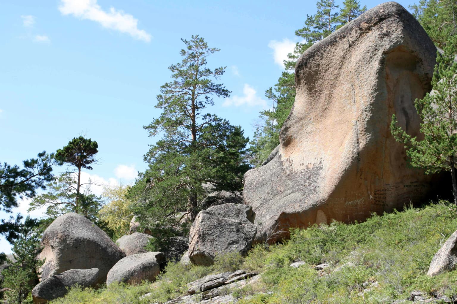 Large rock formations with green vegetation and trees under a clear blue sky