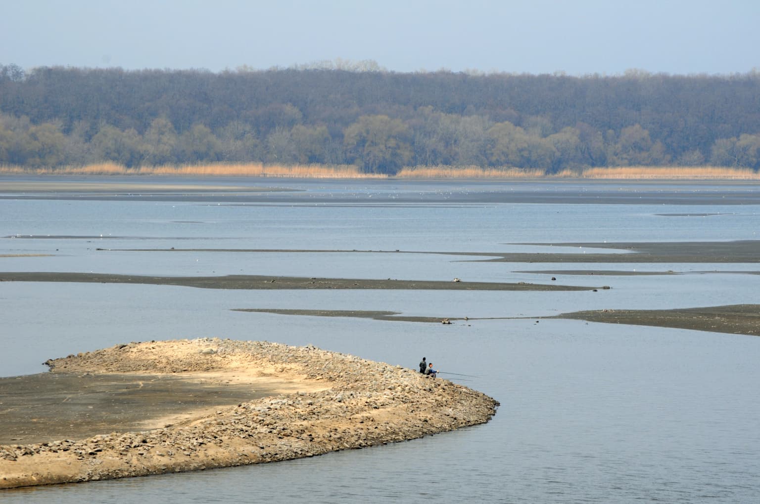 Wide view of Sula River in Lower Sula National Nature Park with sandy peninsula extending into water and forested shoreline in background