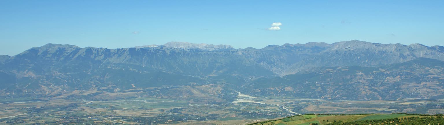 Wide panoramic view of mountain ranges with valleys and a clear blue sky in Lurë-Dejë National Park