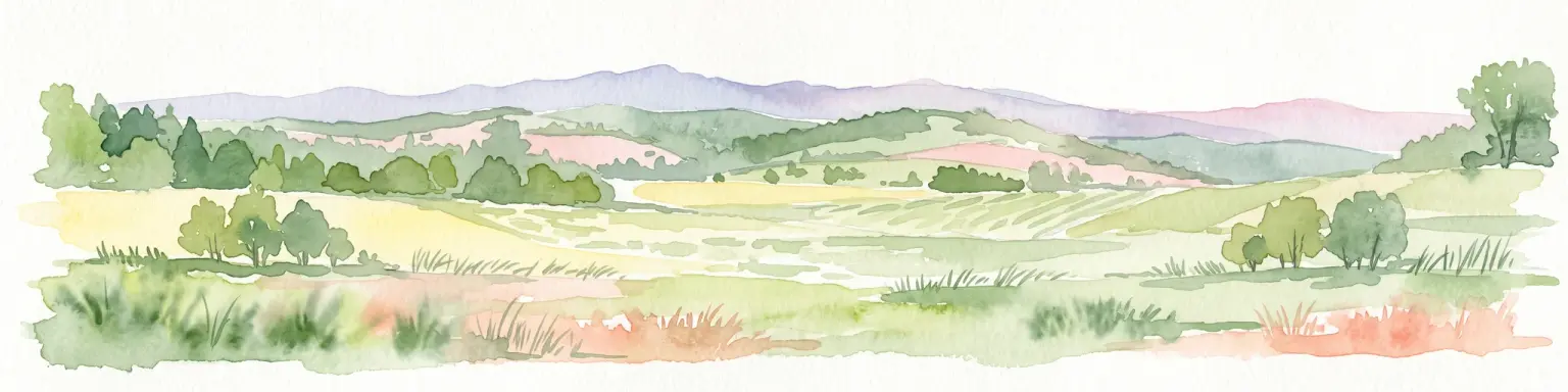 Una pintura horizontal en acuarela que representa un paisaje suave y ondulado con campos verdes, grupos de árboles y montañas lejanas en tonos lavanda bajo un cielo pálido.