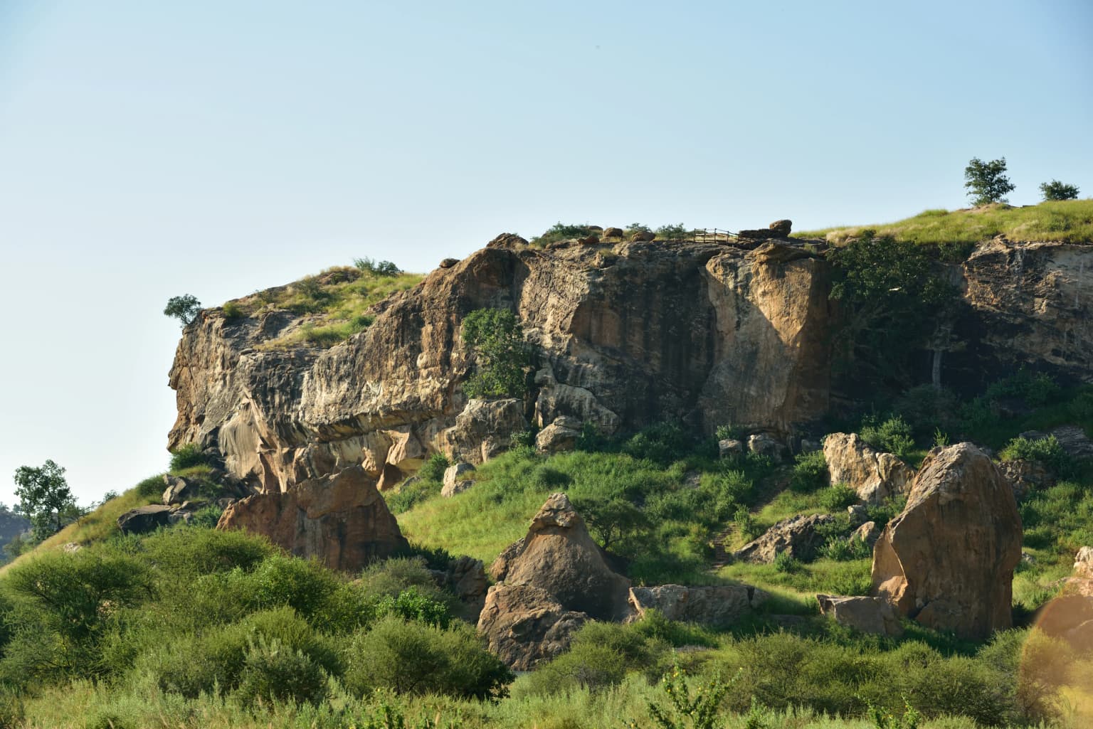 Rocky cliffs with patches of green vegetation overlooking the Limpopo River under a clear blue sky