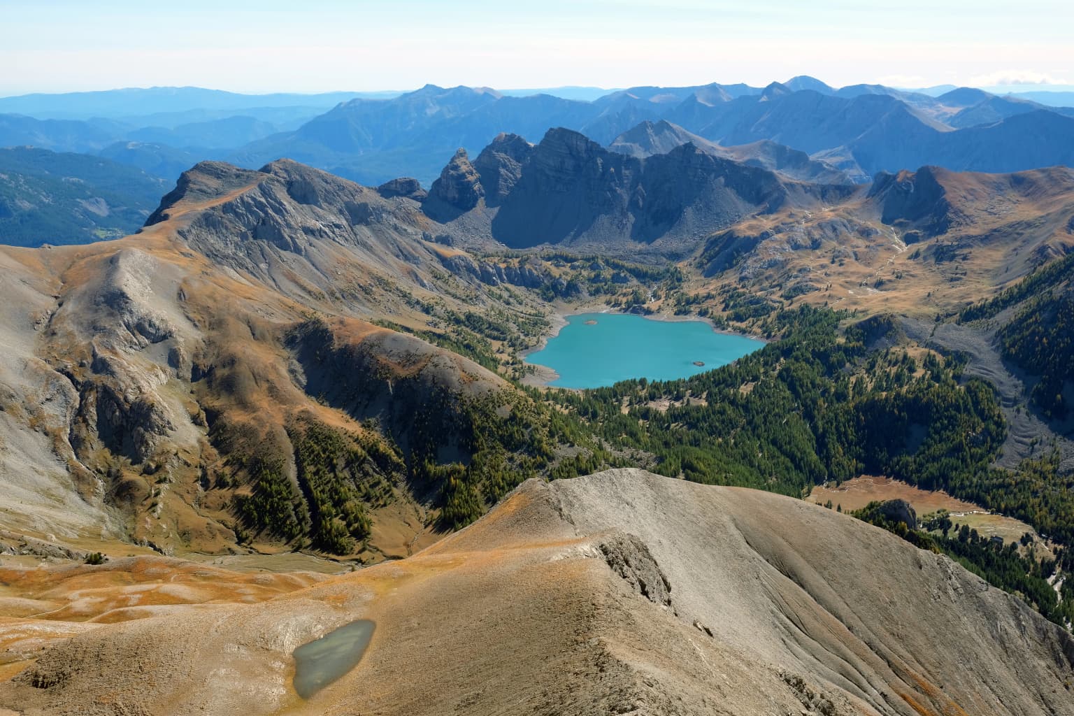 Panoramic view of Lake Allos surrounded by mountain peaks from Mont Pelat summit