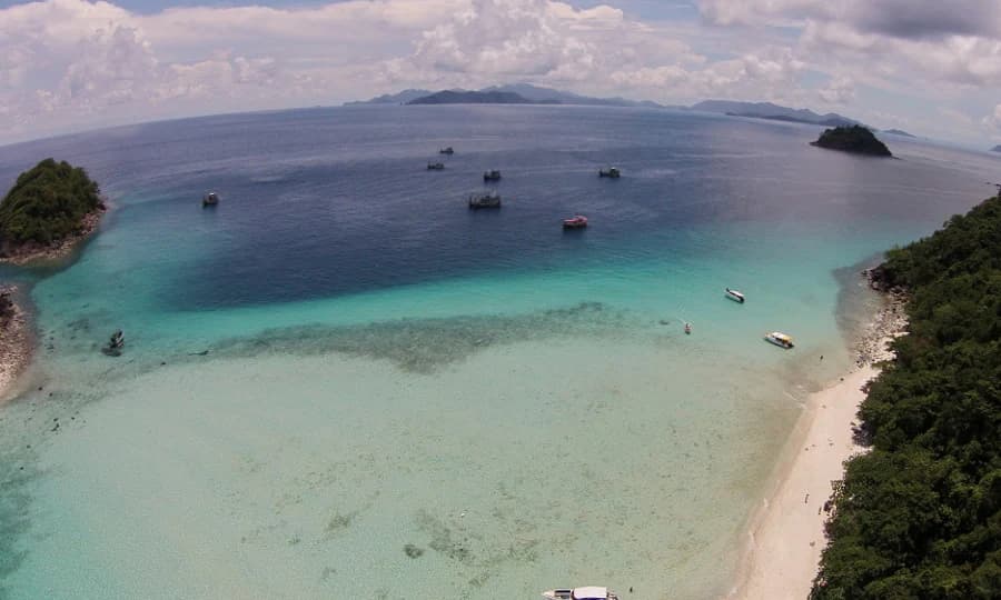 Vista aérea que muestra agua turquesa, múltiples islas, barcos y una playa de arena en el Parque Nacional Mu Ko Chang