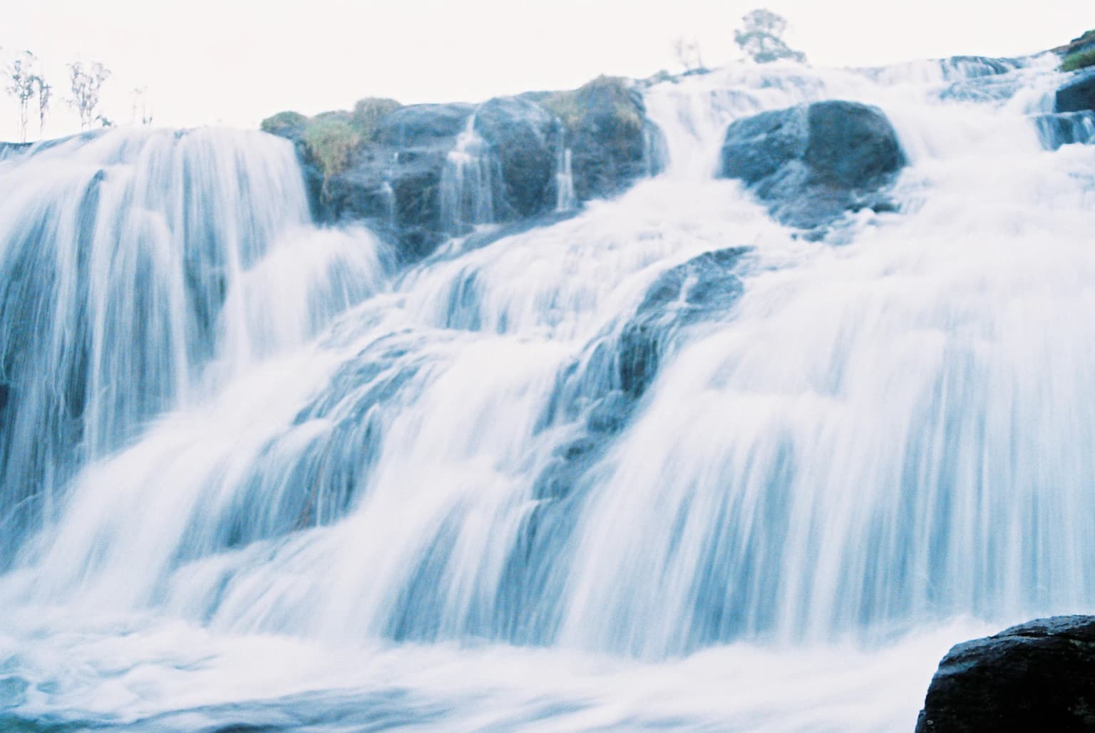 A multi-tiered waterfall cascading down rocky formations with flowing water