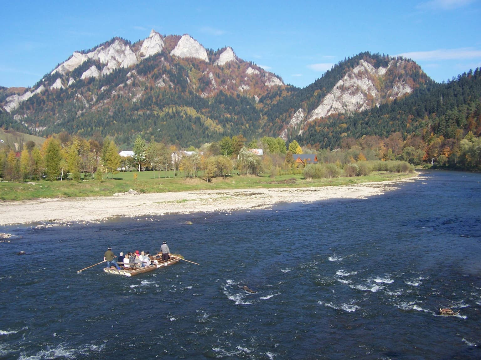 People rafting on a river with mountains and trees in the background