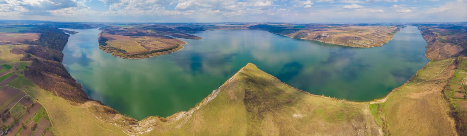 Aerial view of the Dniester River winding through green and brown hills under a partly cloudy sky