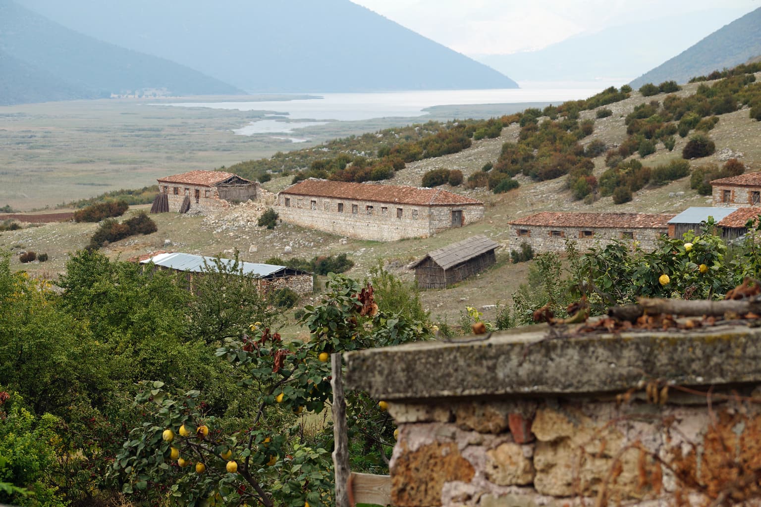 Stone buildings of Zagradec village with Small Prespa Lake and mountains in the background