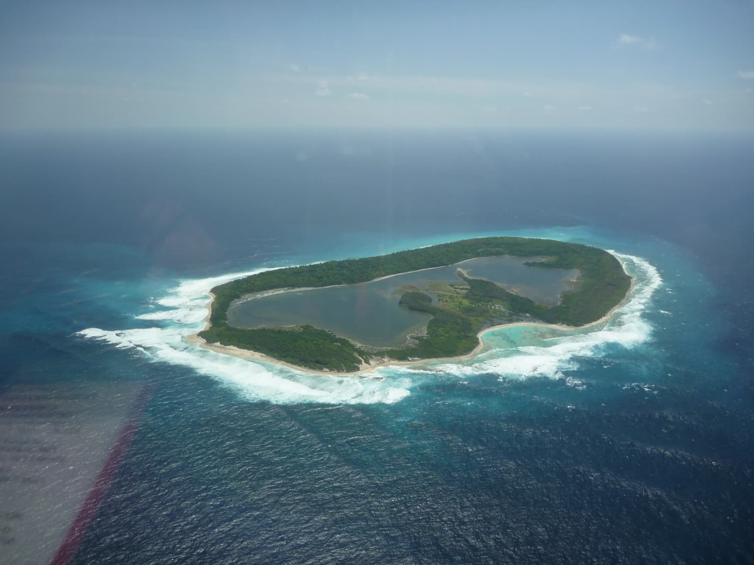 Vista aérea de la isla North Keeling que muestra una laguna central, vegetación costera y aguas oceánicas turquesas con oleaje blanco