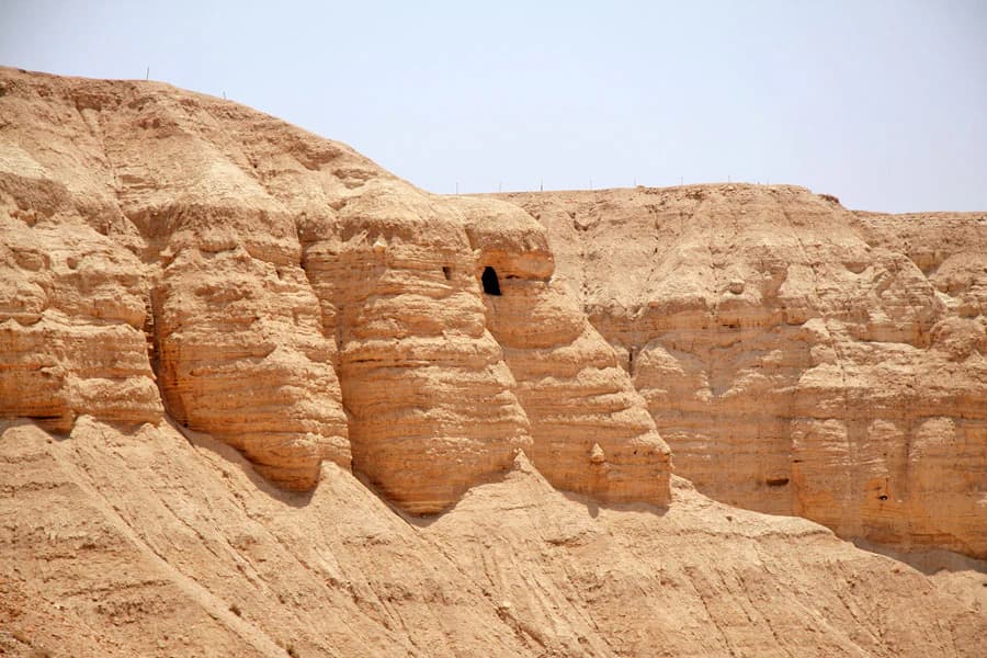 Acantilados desérticos rocosos con aberturas de cuevas visibles en el Parque Nacional de Qumrán