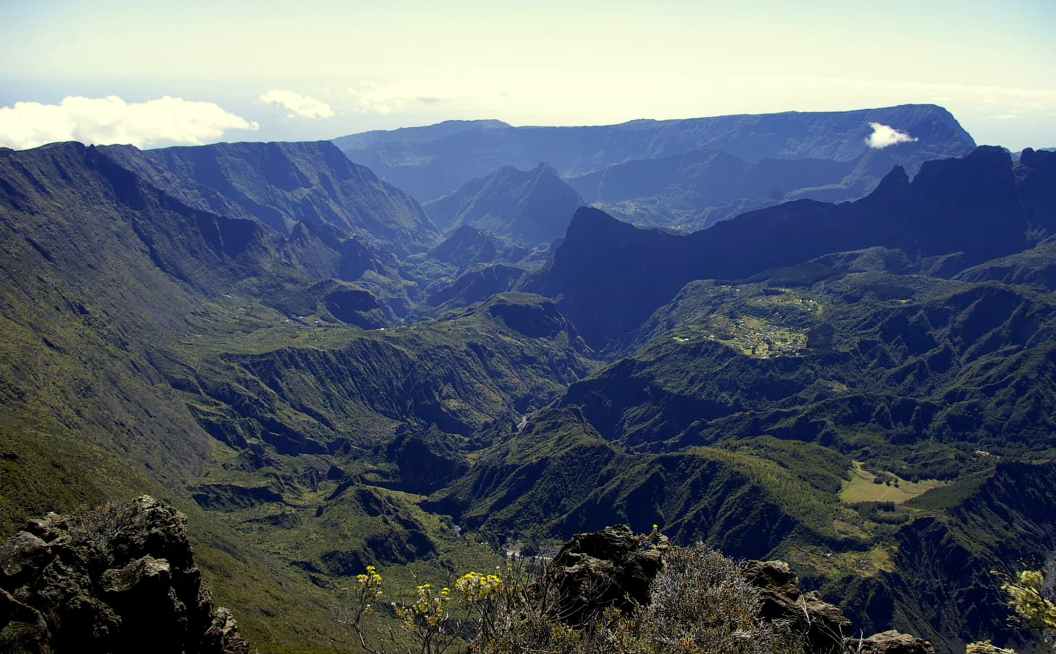 Mountainous landscape with Mafate Cirque, rocky foreground, and deep valleys extending toward distant peaks