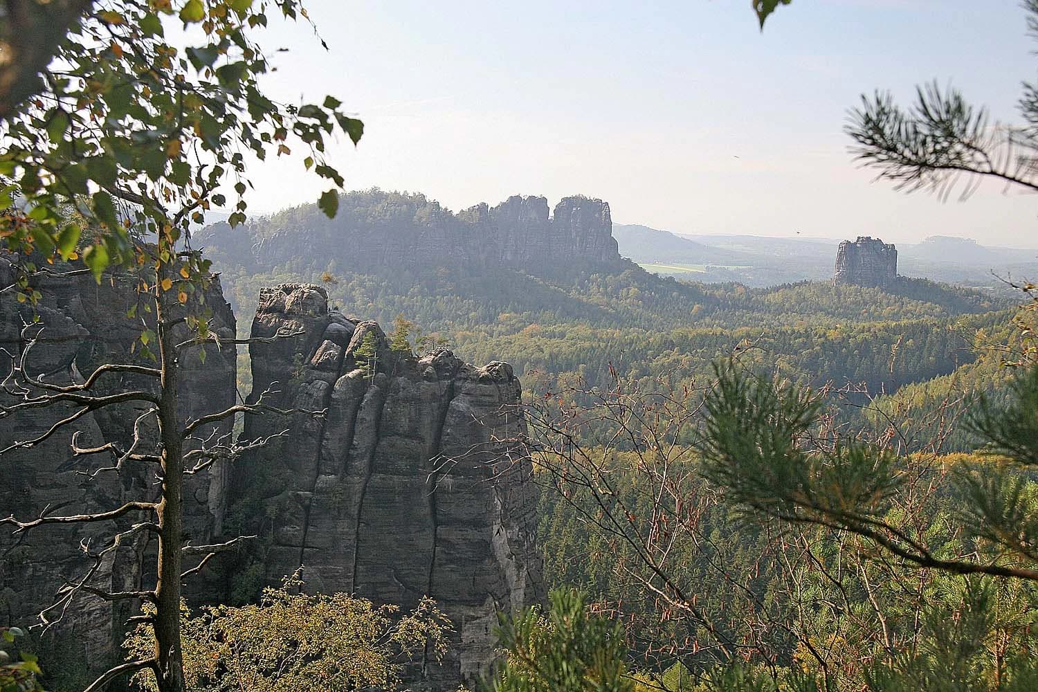 Rock formations and forested landscape with prominent sandstone cliffs in the midground and background