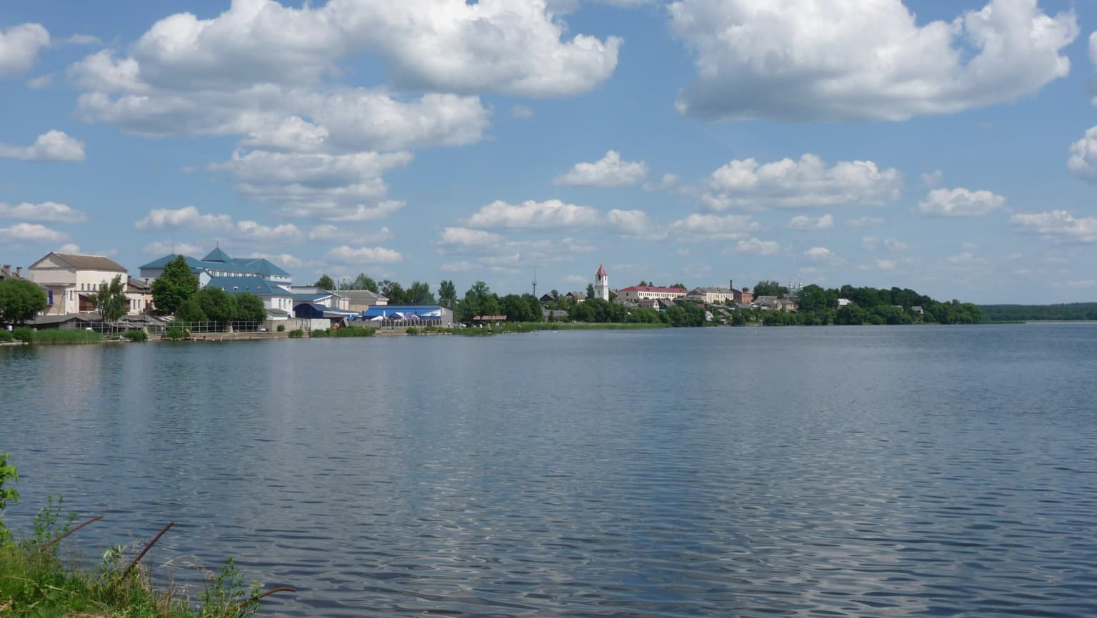 Lake Sebezh with town buildings and greenery visible across the water under a partly cloudy sky