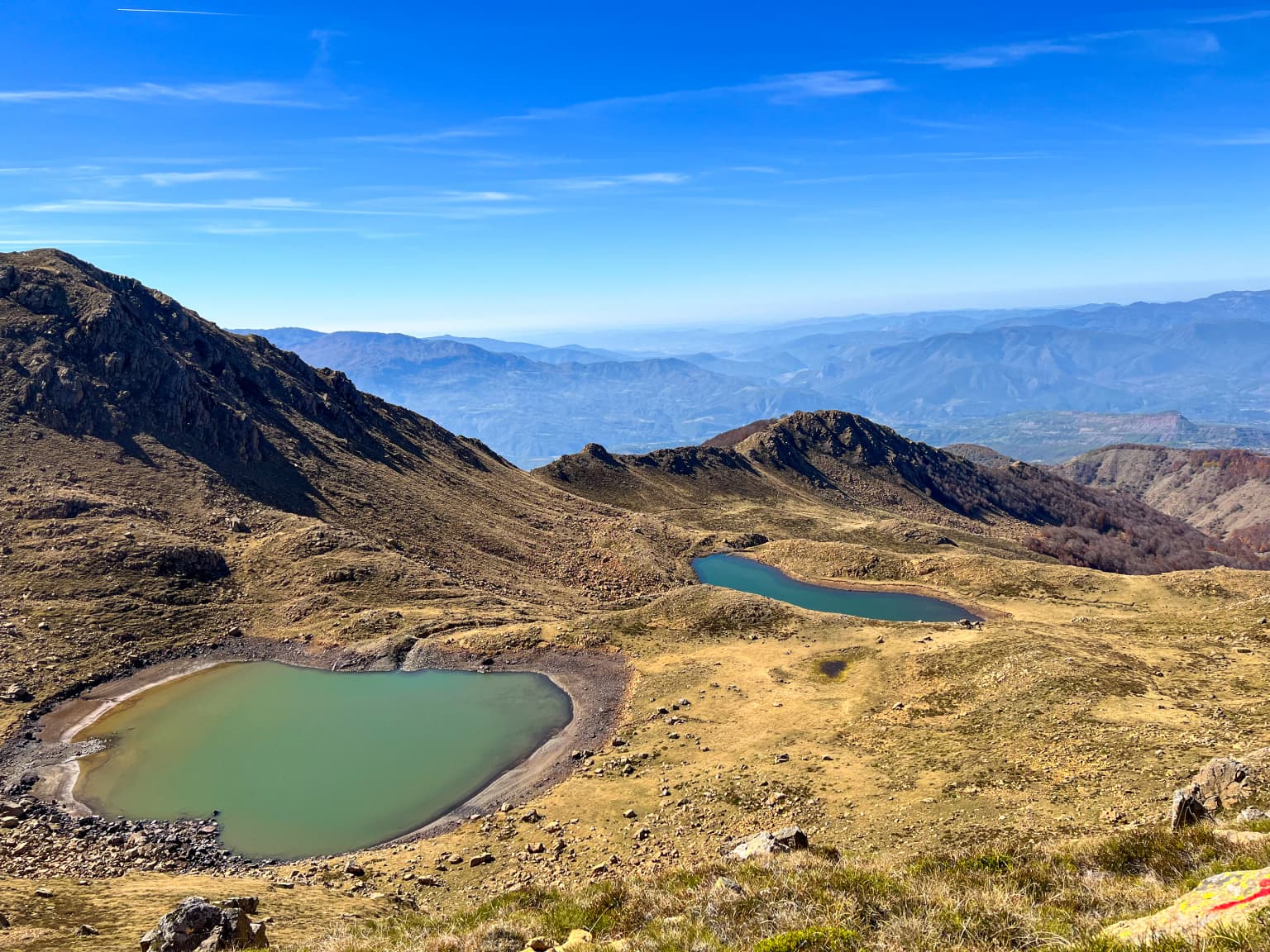 Mountainous landscape with two turquoise lakes surrounded by rocky hills under a clear blue sky