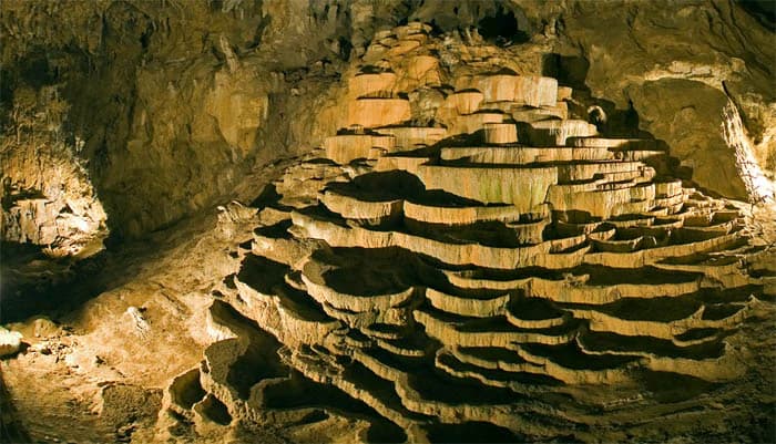 Interior cave scene showing stratified rock formations of precipitated calcium carbonate