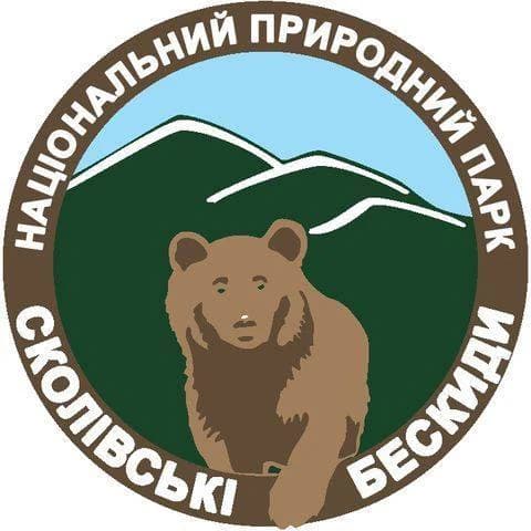 Circular emblem with brown bear in center, green background, blue sky, and Ukrainian text around border