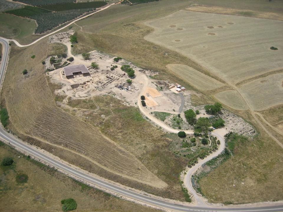 Aerial photograph of Tel Hazor National Park showing archaeological ruins, a building, roads, and surrounding agricultural fields