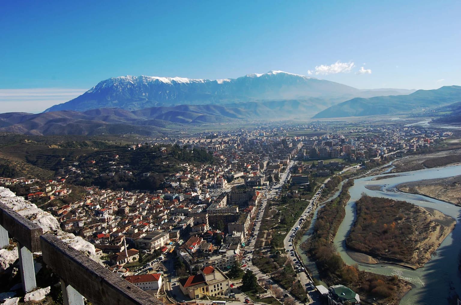 Stone viewing platform overlooking the city of Berat with snow-capped Mount Tomorr visible in the distance under a clear blue sky