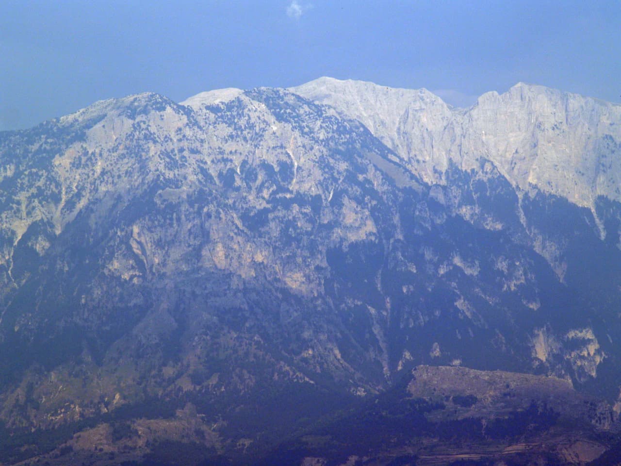 Snow-capped mountain range with rocky terrain under a clear sky