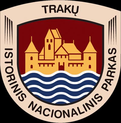 Circular emblem with 'TRAKŲ' text at top, 'ISTORINIS NACIONALINIS PARKAS' text around edges, yellow castle illustration on red background, and blue-white wavy lines representing water