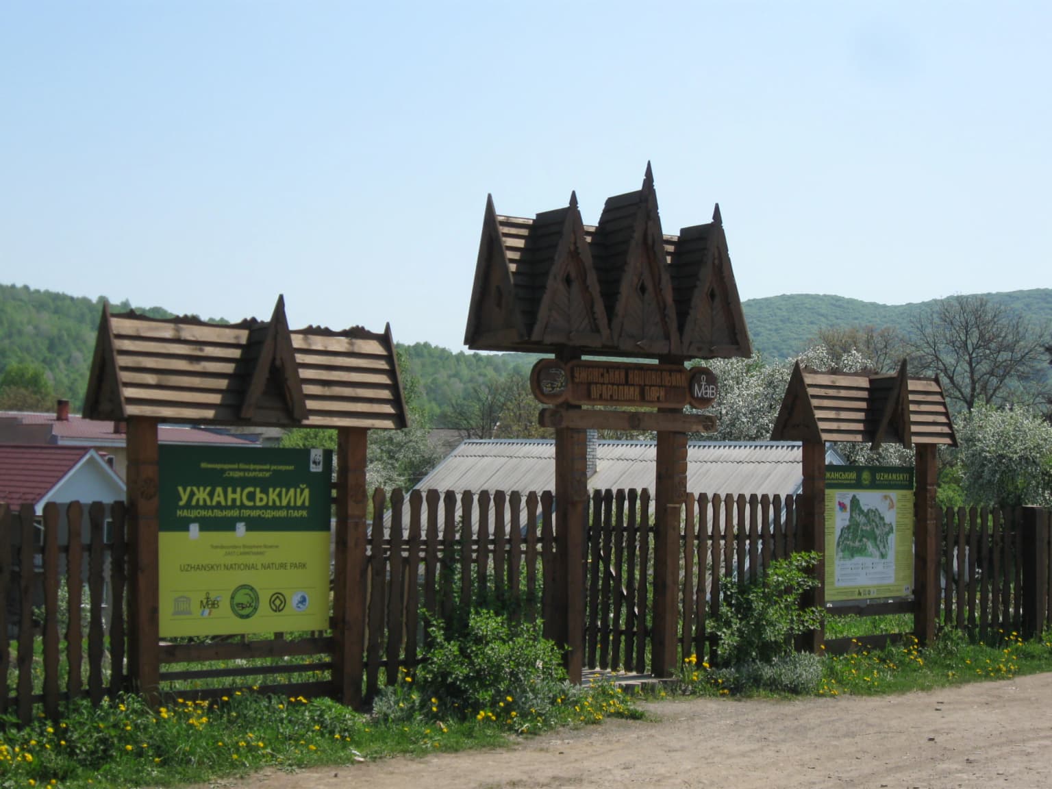 Wooden entrance sign structure with triangular roofs and informational signs at Uzh National Nature Park