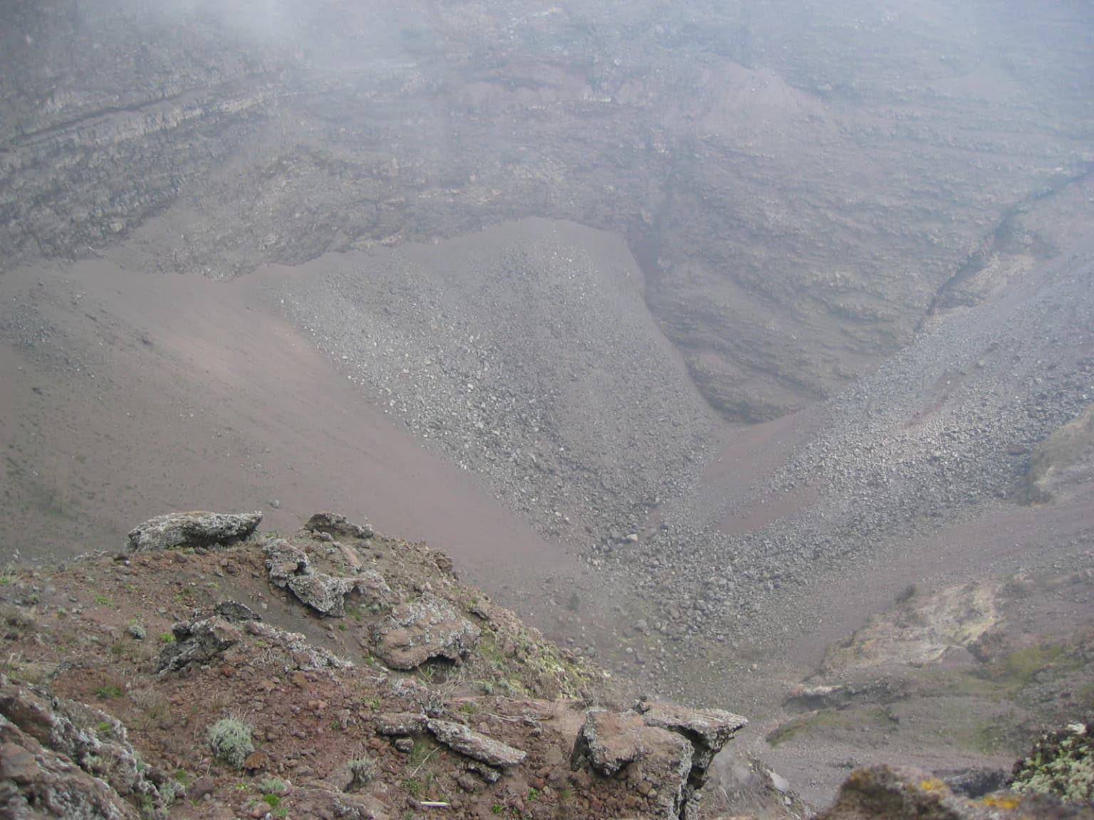 Rocky volcanic crater landscape with mist above the slopes