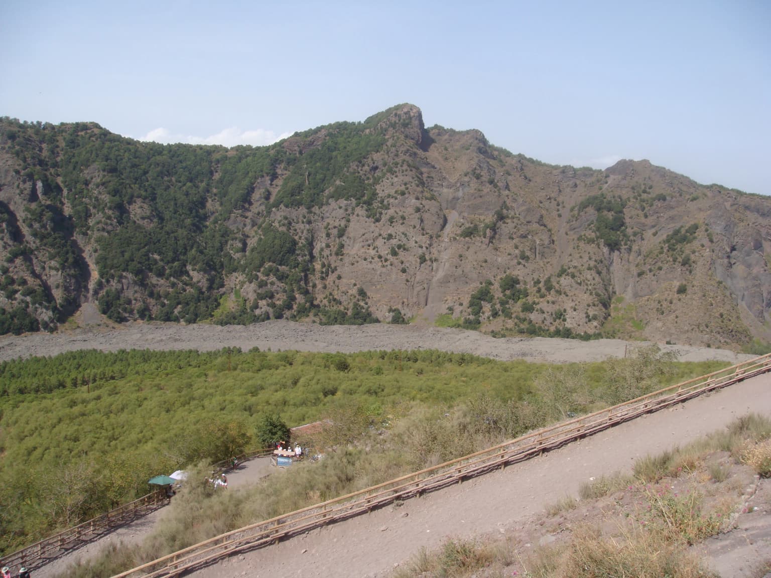 Punta del Nasone peak viewed from Vesuvius crater with rocky mountains, green vegetation, and a dirt path in the foreground