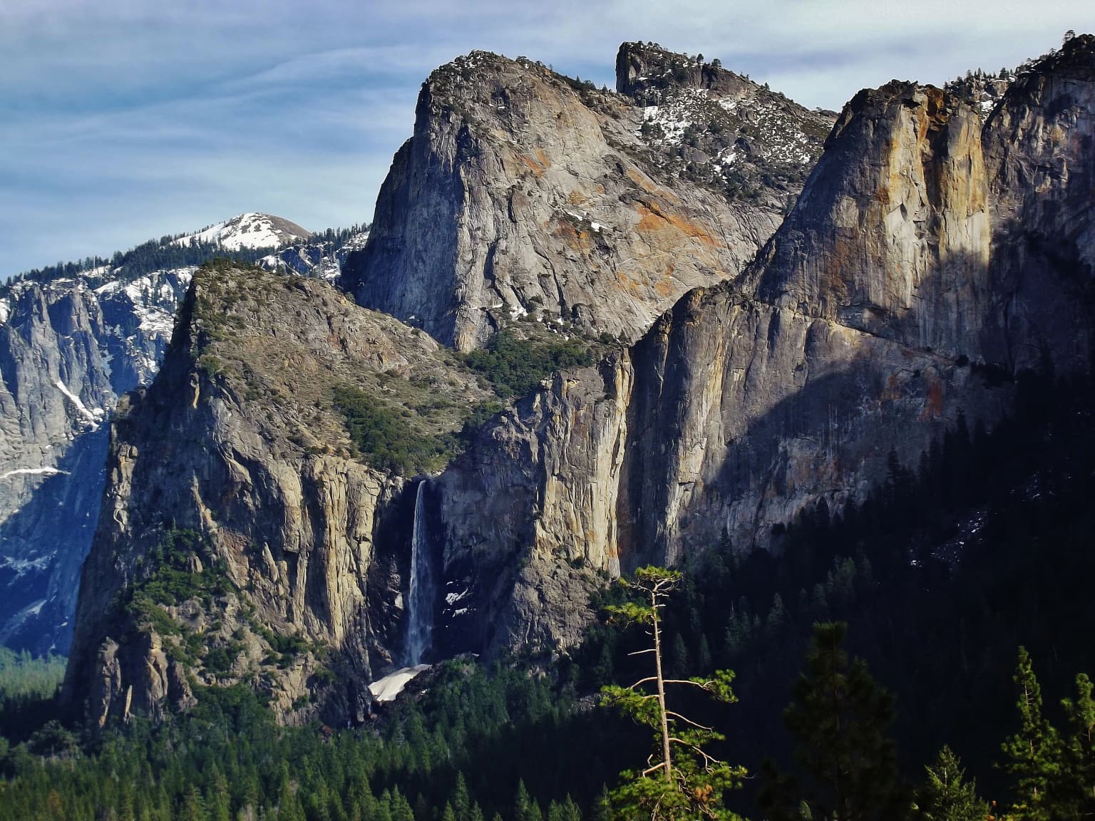 Cascada de Bridalveil cayendo por acantilados de granito con un valle boscoso debajo